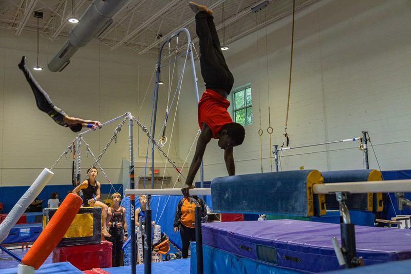 Arlington Tigers gymnast performing handstand on parallel bars at Barcroft